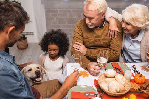 family-enjoying-thanksgiving-dinner-with-dog-nearby