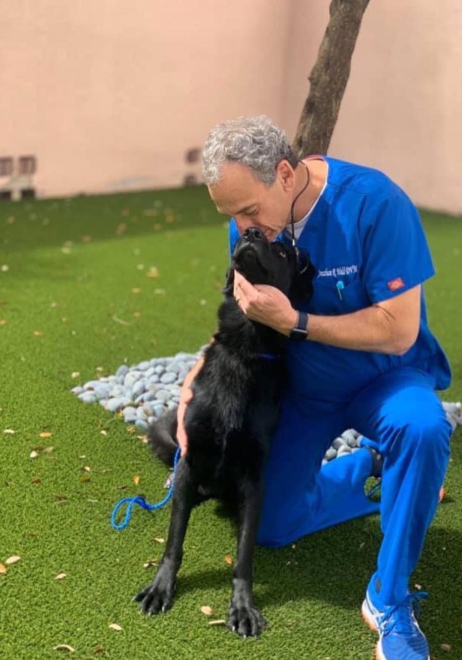 Doctor Kissing Black Dog On Nose Outside