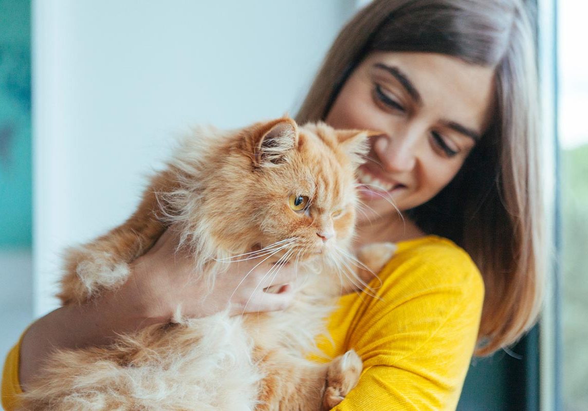 Happy Woman Holding Fluffy Tabby Cat